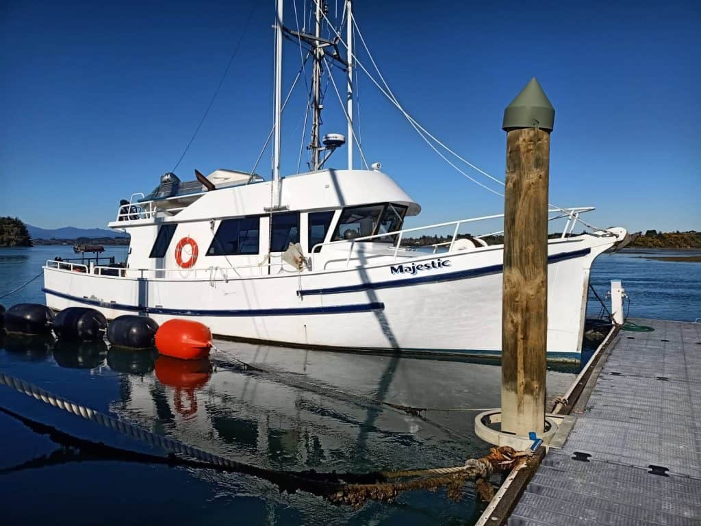 The boat Majestic moored in Motueka with land and the sea in the background