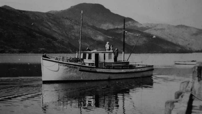 Black and white photo of a wooden boat with hills in the distance