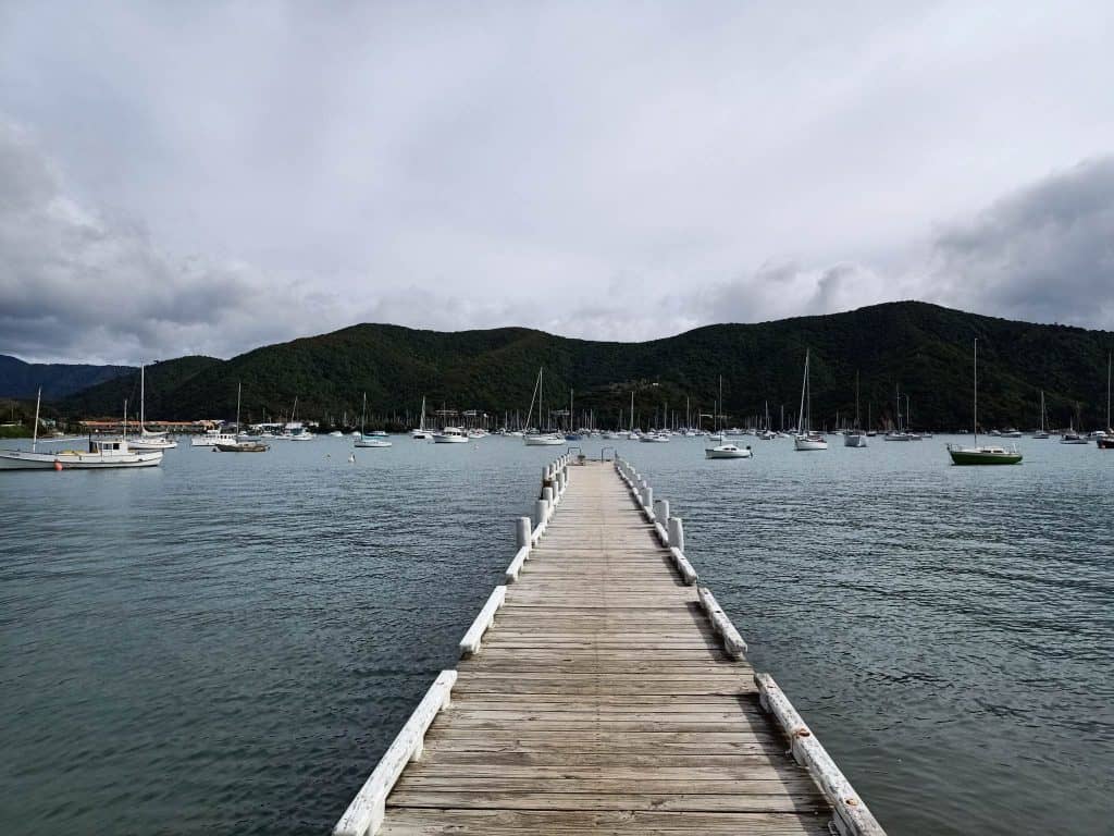 View looking down the wharf towards boats on moorings in Waikawa Harbour