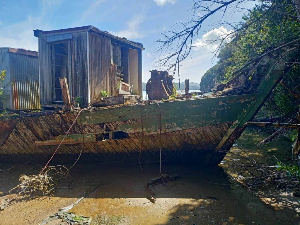 Close up view of Kohi, a wooden scow. The boat is beached and is in disrepair. Only the bow can be seen.