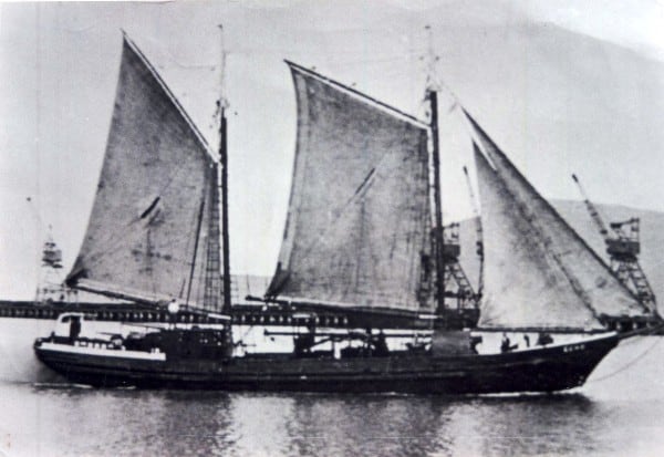 Black and white image of the scow Echo viewed from the side with her sails up.