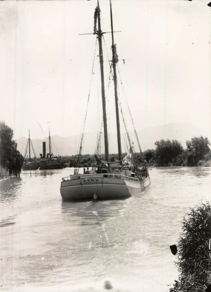 Black and white image of the Echo scow travellign away from the camera down a river.