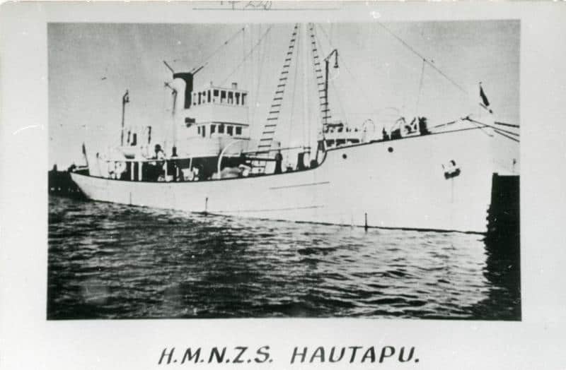 Black and white image of a photo of HMNZ Hautapu. Shown from the side across some water. Though to be photographed in Lyttleton in the 1940s