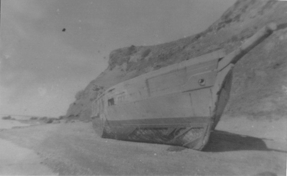 Black and white image of the scow Altair on a beach seen from the side of the bow.