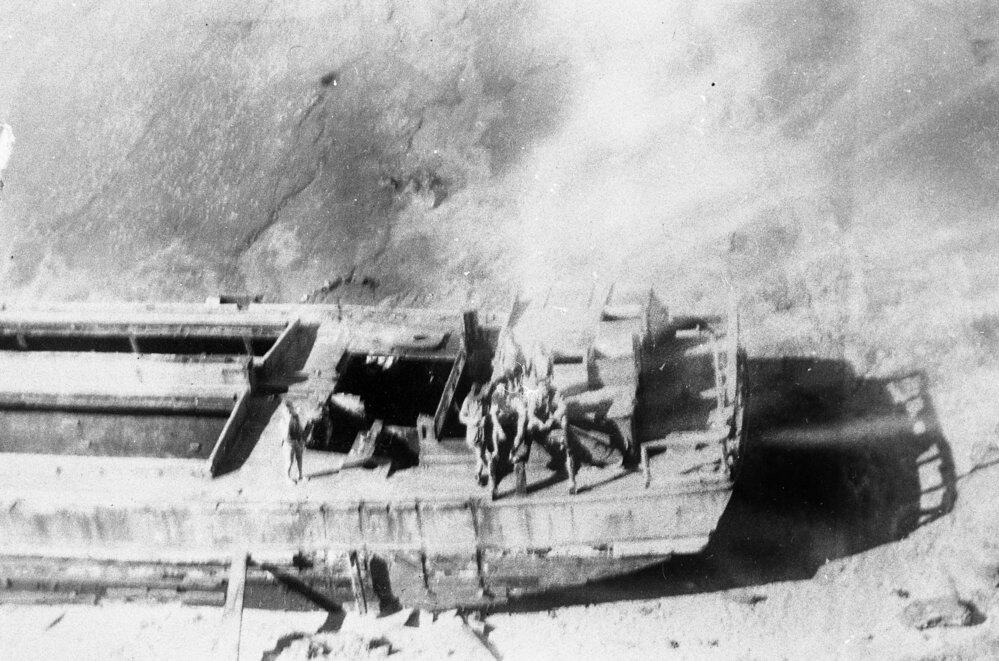 black and white image the scow Altair on the beach. The image is taken from above and shows the stern of the boat.