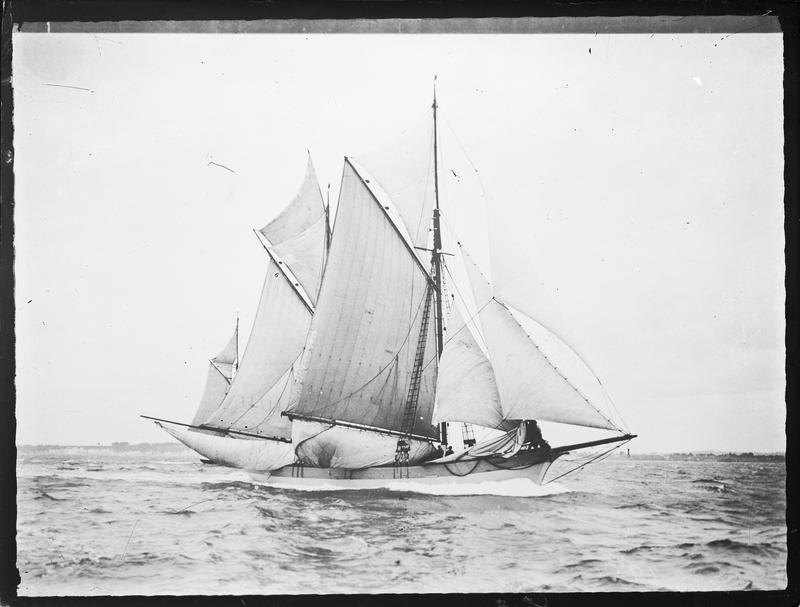 Black and white image of the scow vesper seen from the side with full sails hoisted.