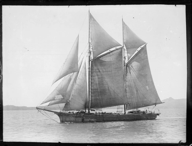 Black and white image of the scow vesper under sail and seen from the side.