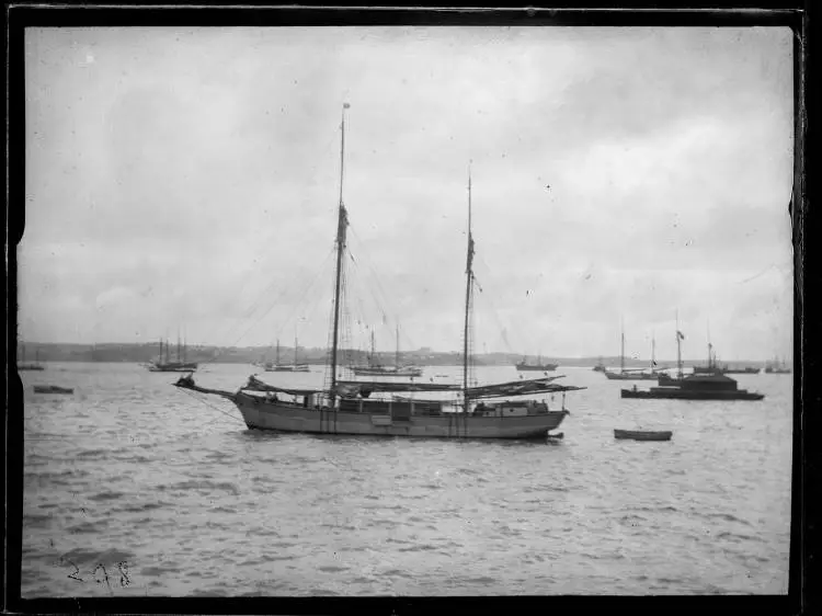 Black and white image of the scow Vesper on a mooring in the Waitematā Harbour. Seen from the side her sails are down.